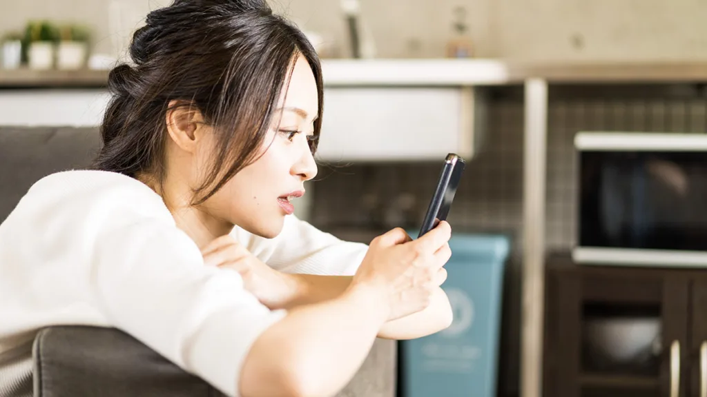 部屋でスマホを使う若い女性